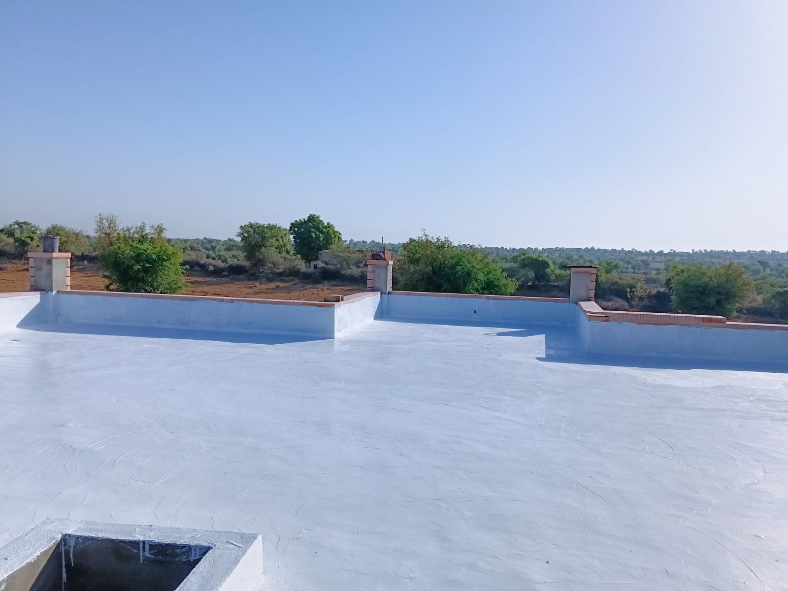 Completed terrace waterproofing showing coated parapet and water tank inlet